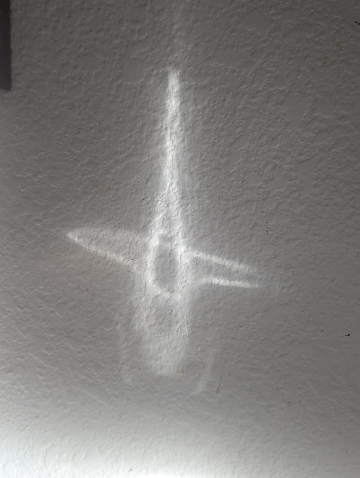 A triangle-like shape made by reflected light on a textured wall