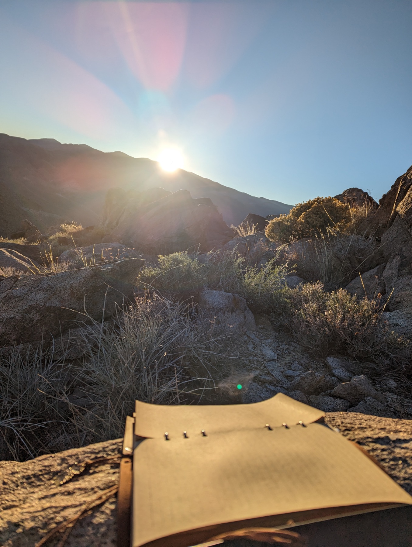 An open journal facing the rising sun in a mountain landscape